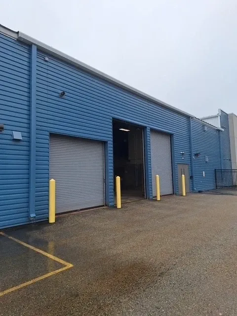 Blue facility exterior with open roll-up bay door